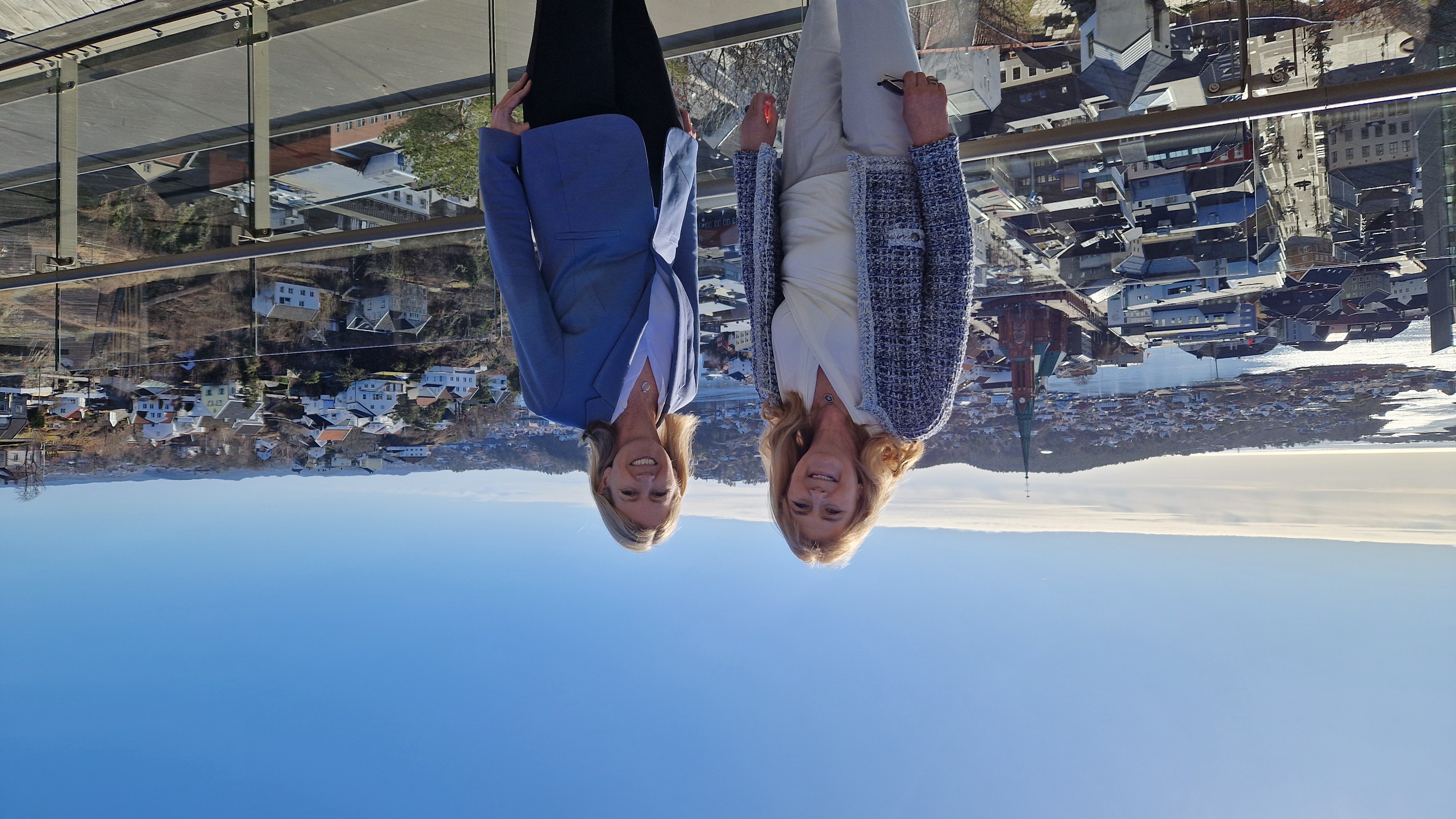 To smilende mennesker stående ved siden av hverandre, med utsikt over Arendal i bakgrunnen