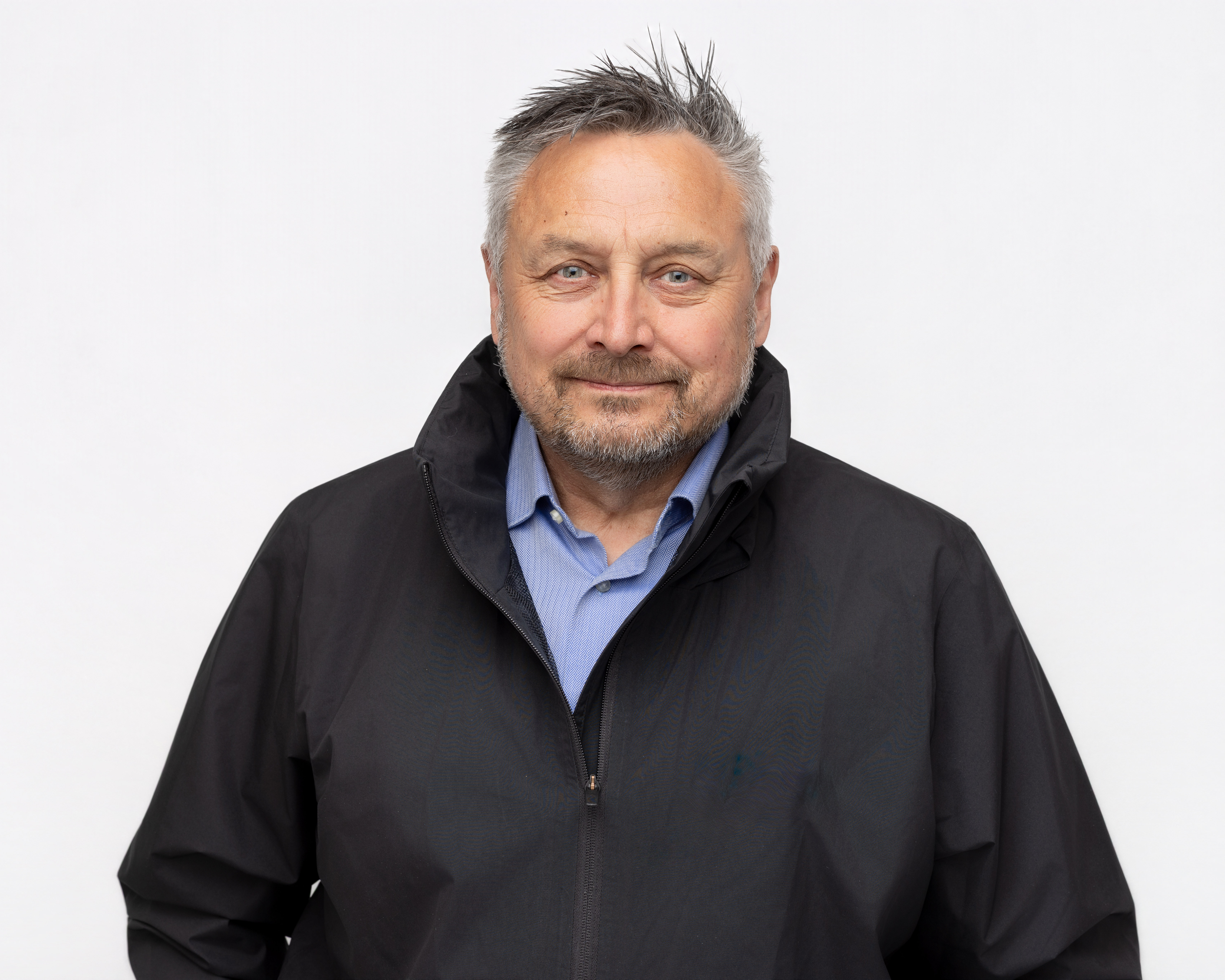 Mann i mørk jakke ser mot kamera. 