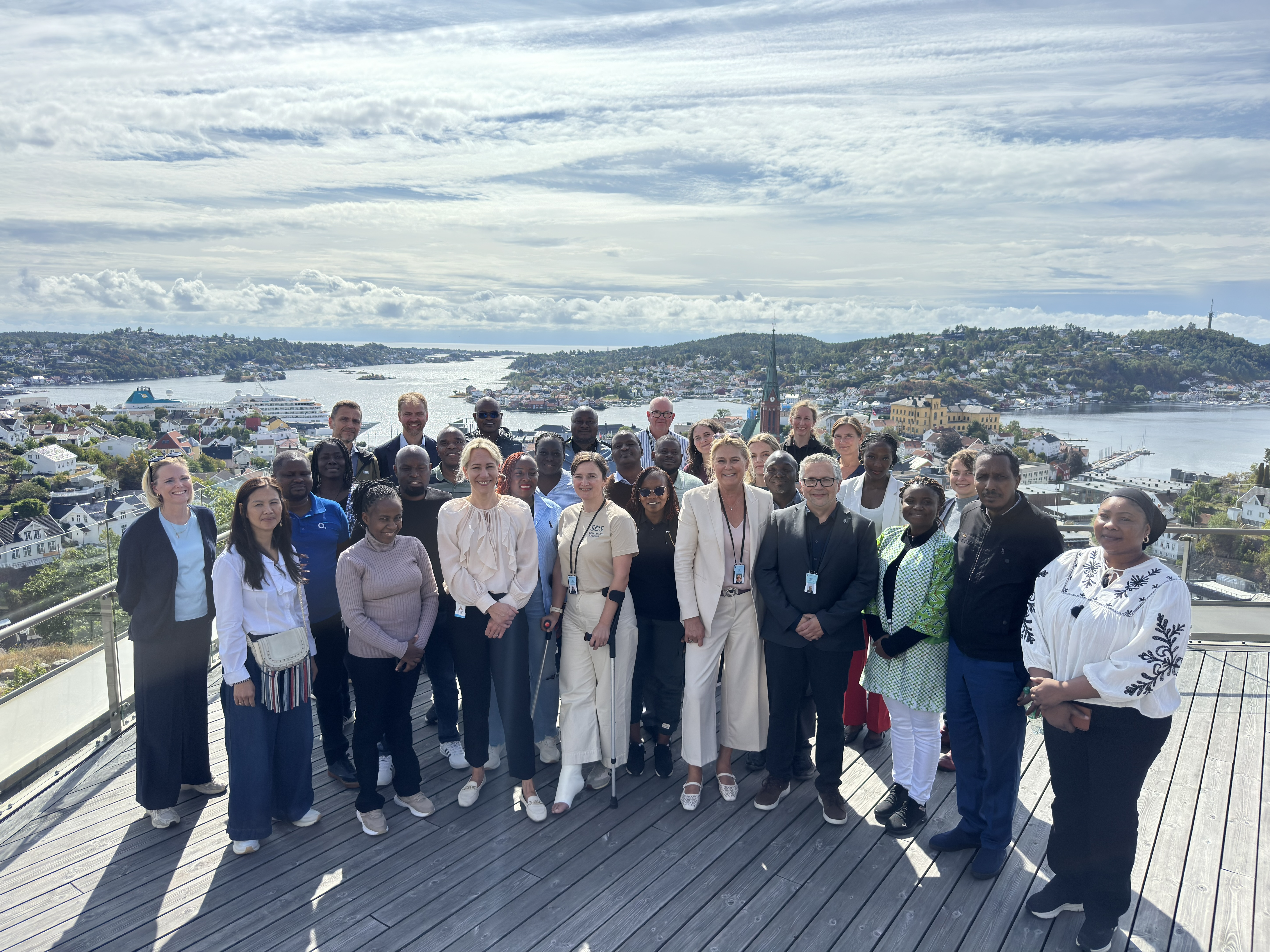 Gruppebilde av deltakere fra Ghana, Kenya, Miljødirektoratet, Norad, Arendal kommune, GRID-Arendal og Statsforvalteren i Agder på utsiktsterrassen ved Statsforvalterens kontor på Fløyheia i Arendal.