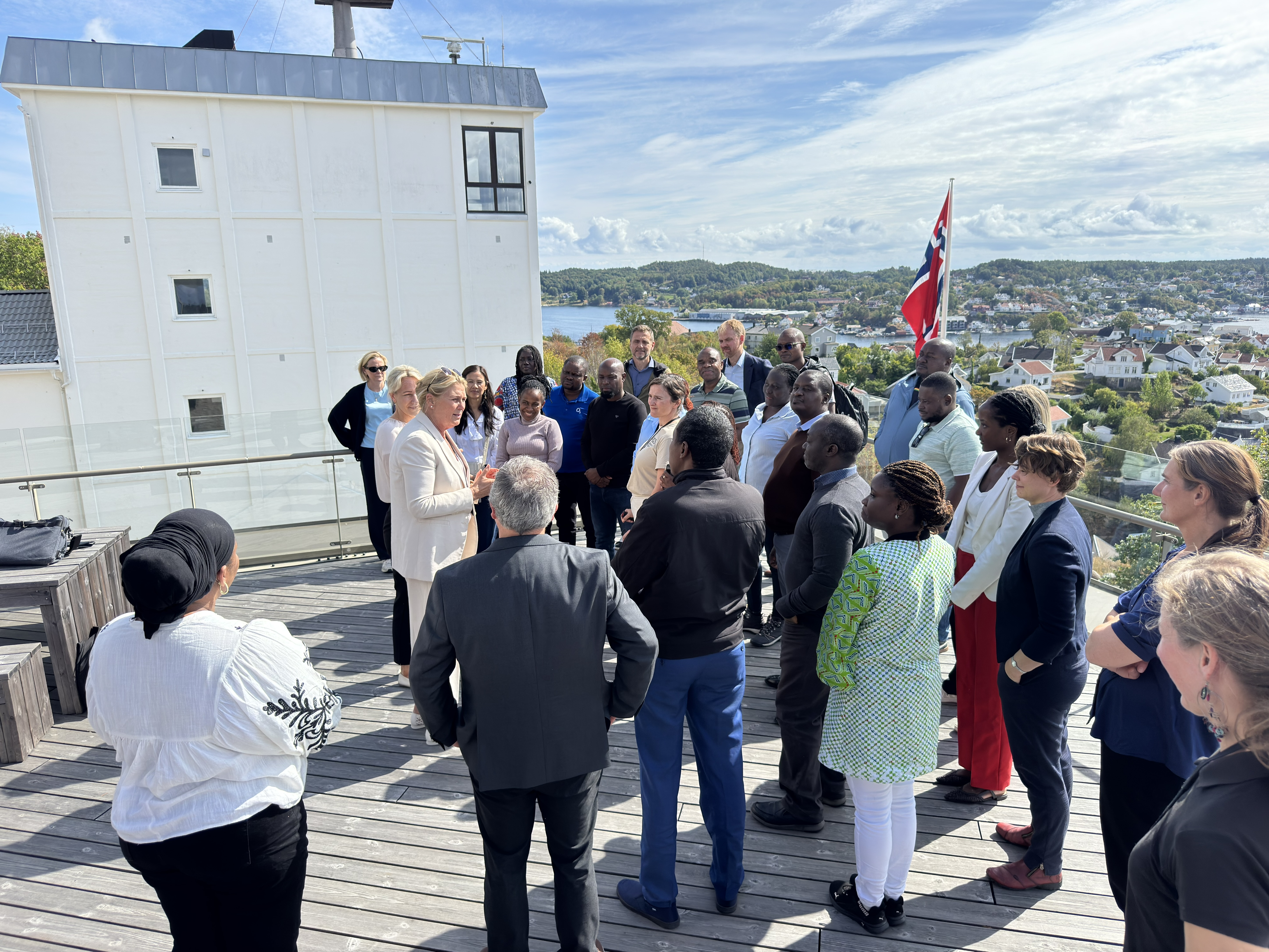 Deltakere fra Ghana, Kenya og norske samarbeidsaktører samlet på takterrassen ved Statsforvalterens kontor på Fløyheia, hvor de får en orientering om Agder og besøksprogrammet.