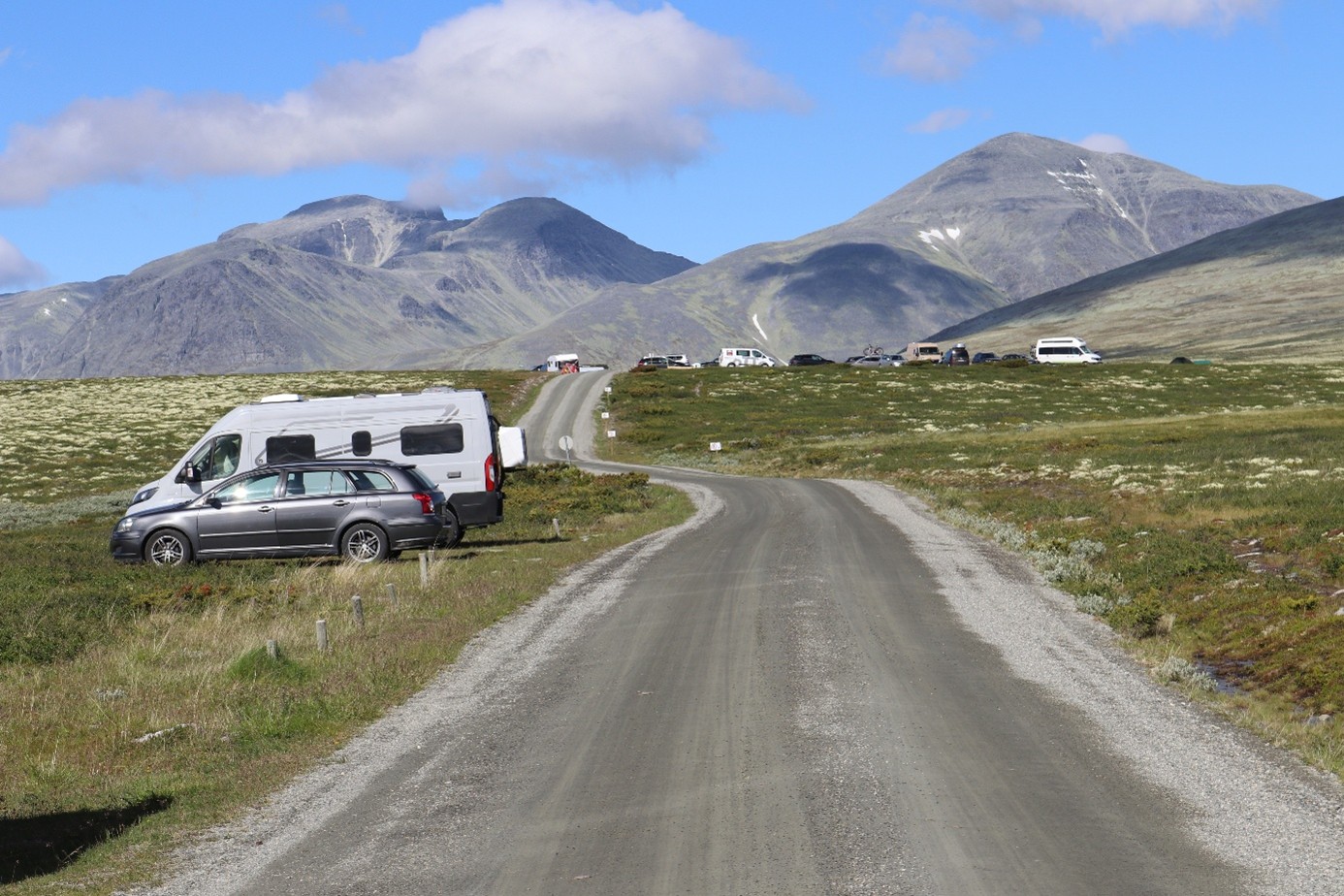 Biler ved vei i fjellandskap. Foto.