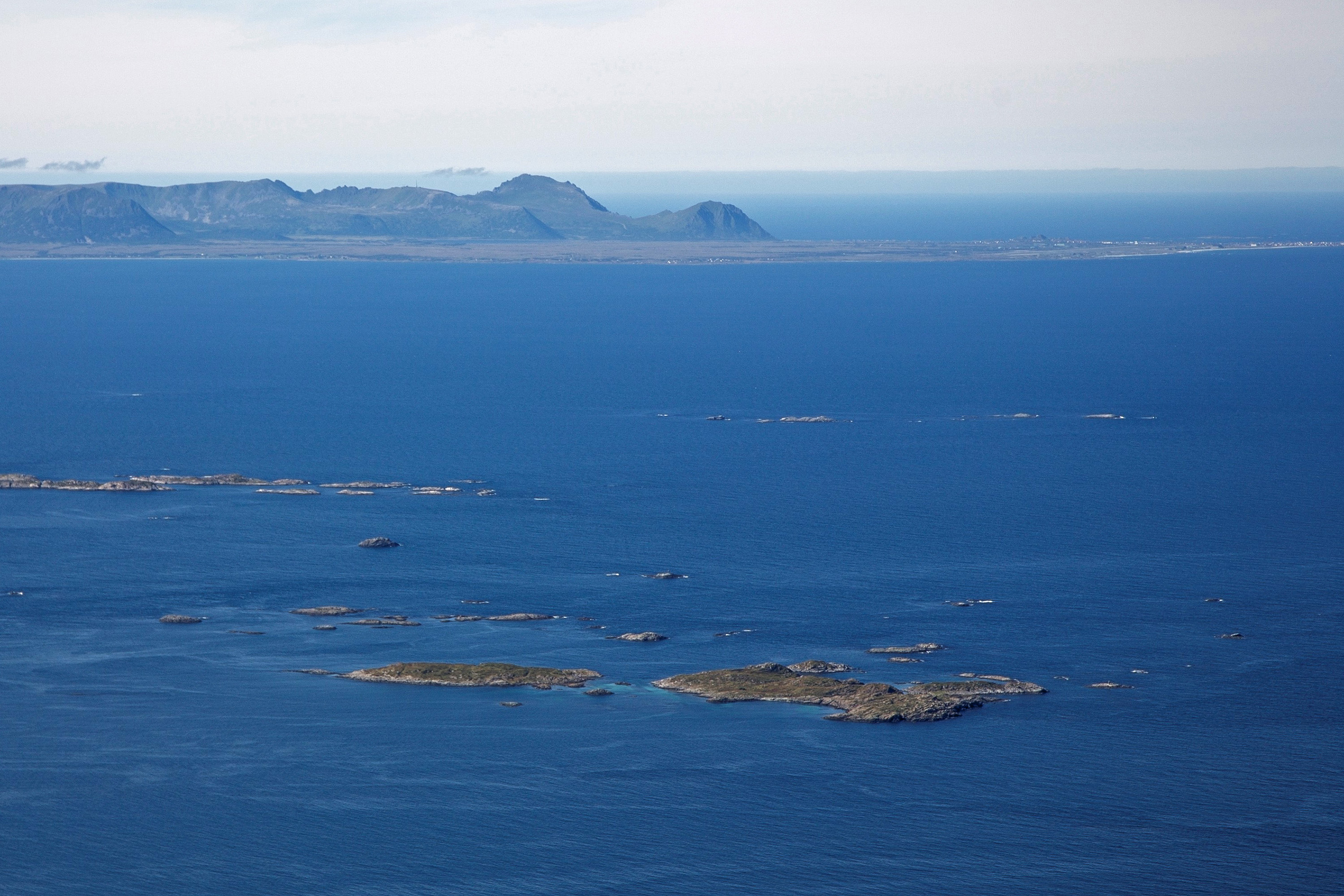 Viser en bred fjord, hav og stort nes på lang avstand.