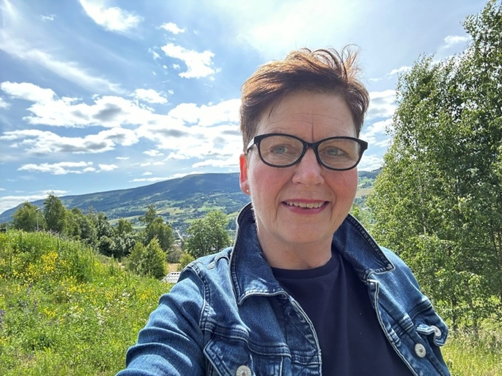 Eli Blakstad i nærbilde, i grønne landskap i Gudbrandsdalen.