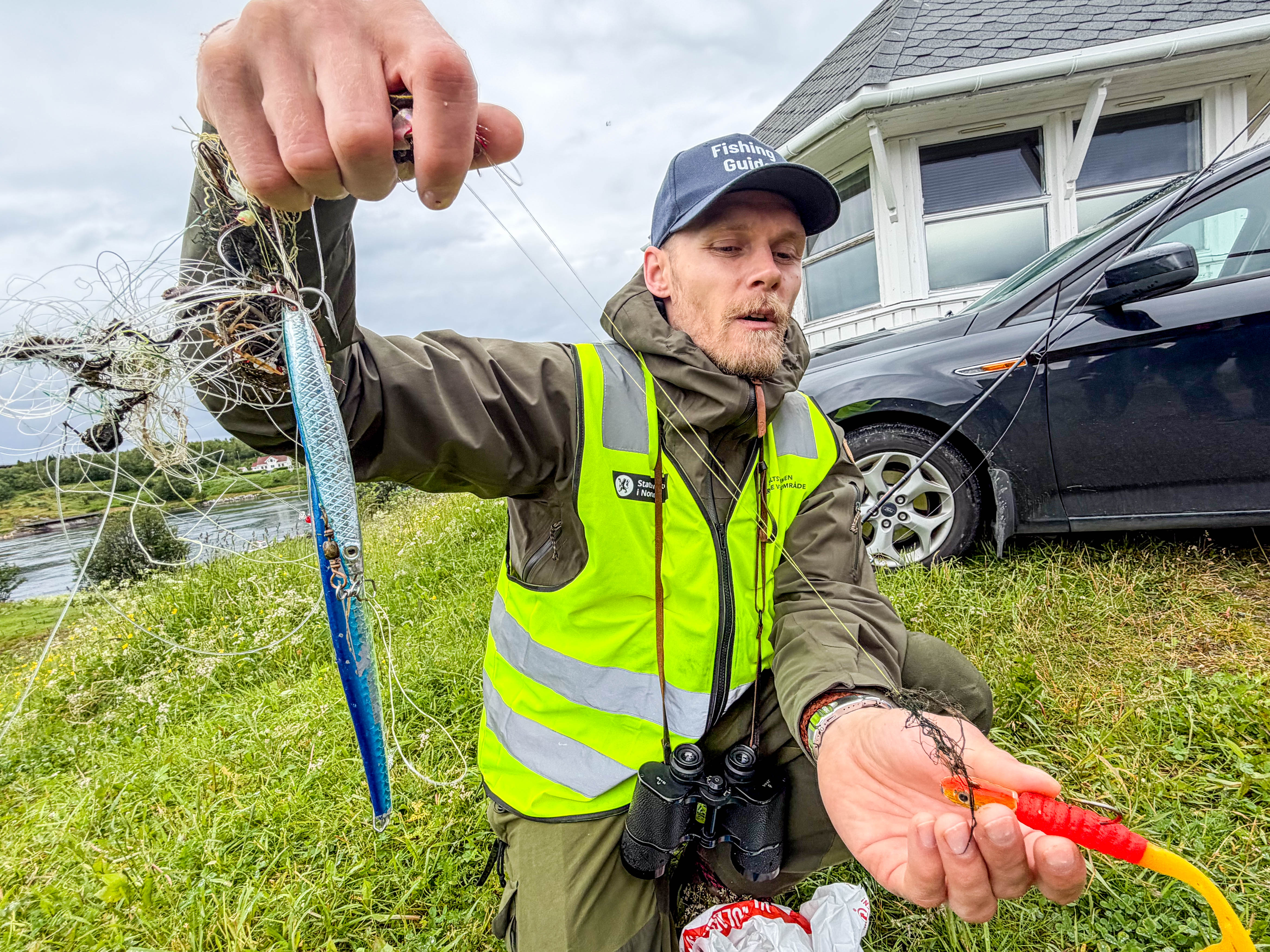 En mann holder opp fiskekroker og sene som er krøllet sammen. 