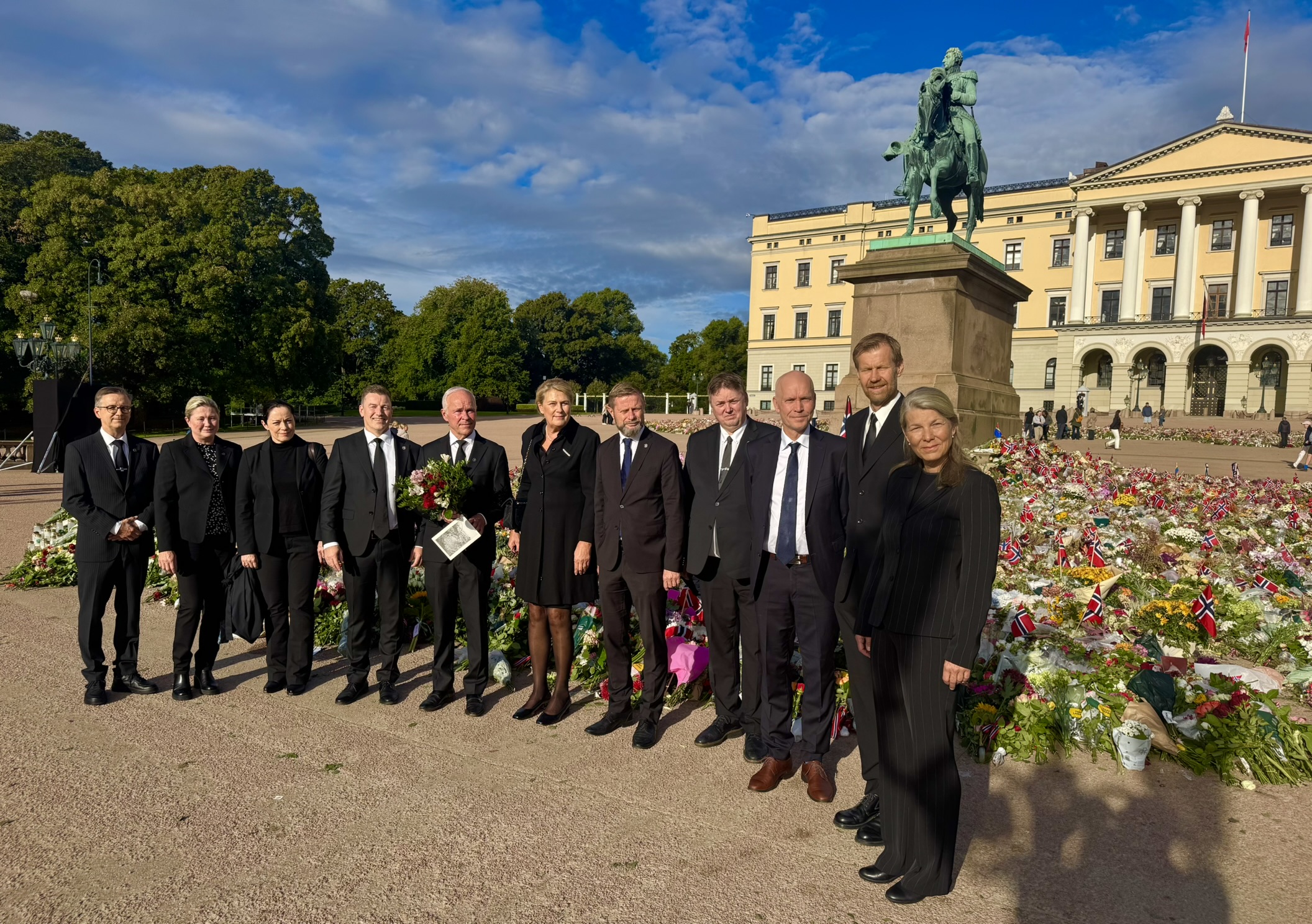 Statsforvalterne og Sysselmesteren på Svalbard står samlet ved blomsterhavet på Slottsplassen foran Slottet i Oslo før defileringen ved Kong Harald Vs båre i Slottskapellet.