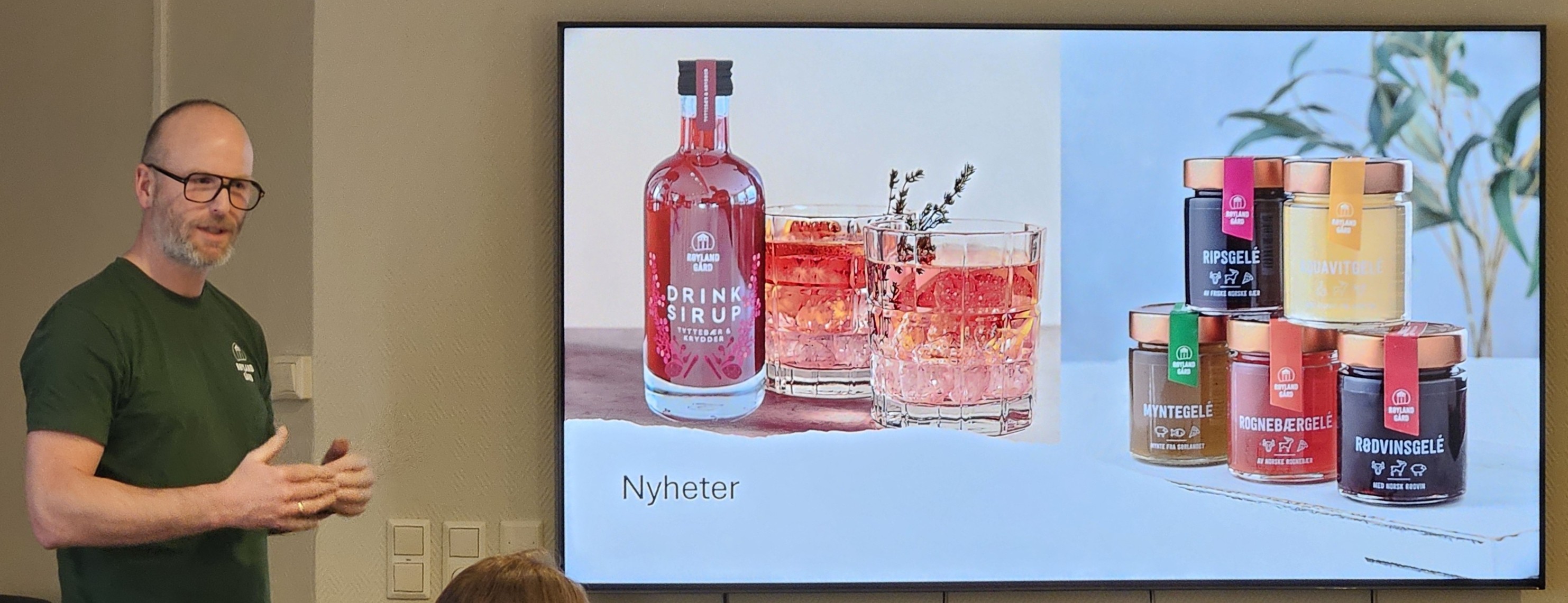 Mann står ved siden av skjerm som viser to bilder. Et bilde viser en flaske rød drikke der det står "Drinksirup" på etiketten og to glass med rød drinker med isbiter. Et bilde viser fem glass med ulike slag gelé.