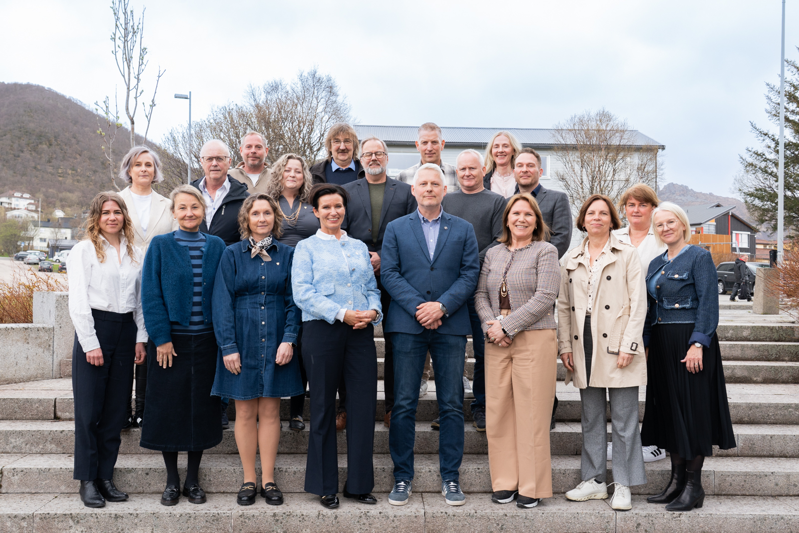 Møtedeltakerne fra Statsforvalteren i Nordland og Øksnes kommune. Foto: Hege Abrahamsen / Øksnes kommune. En gruppe mennesker står oppstilt utendørs i en trapp. I bakgrunnen kan man se noen hus.