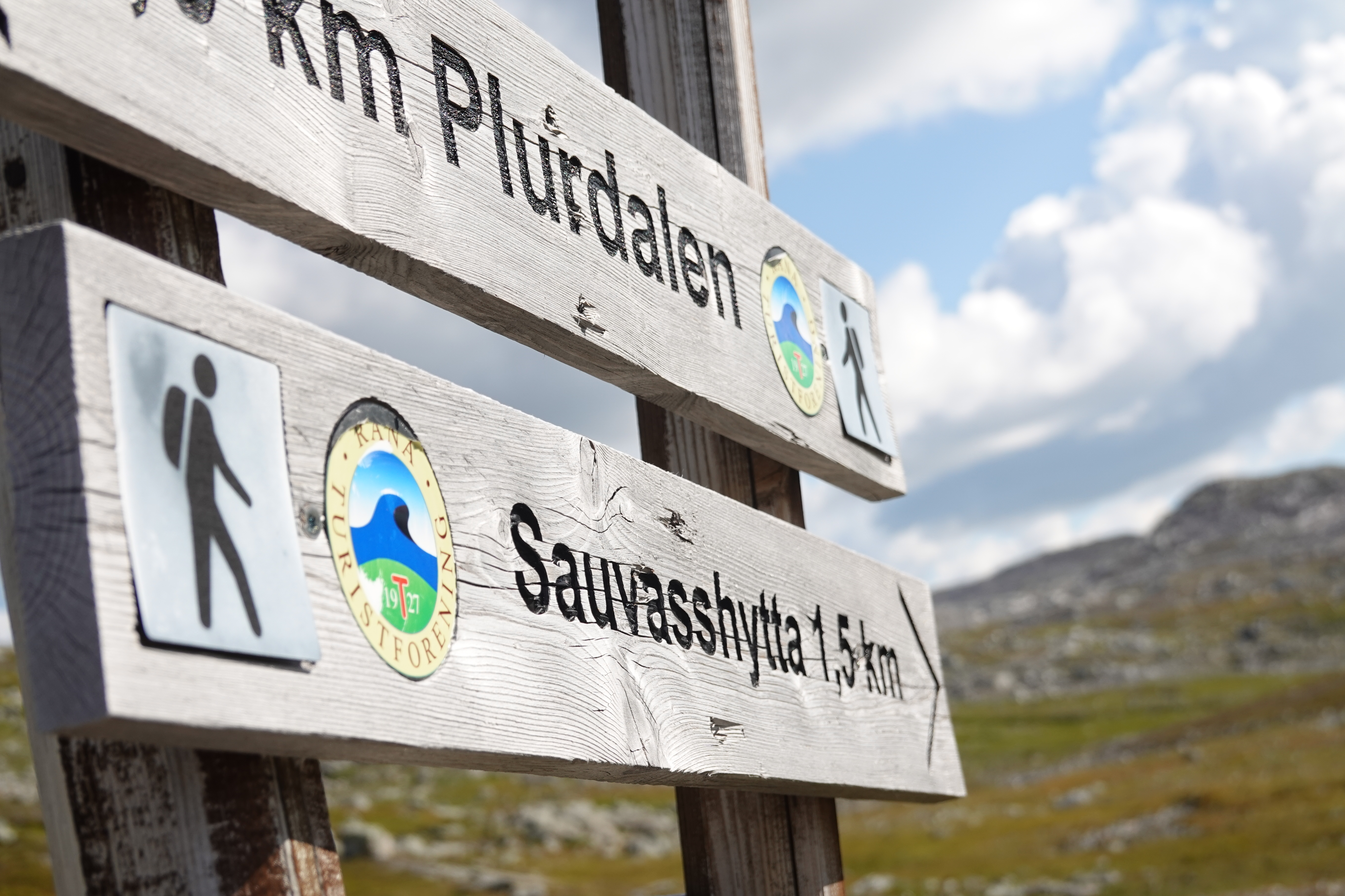 Treskilt med fjellandskap i bakgrunnen. 