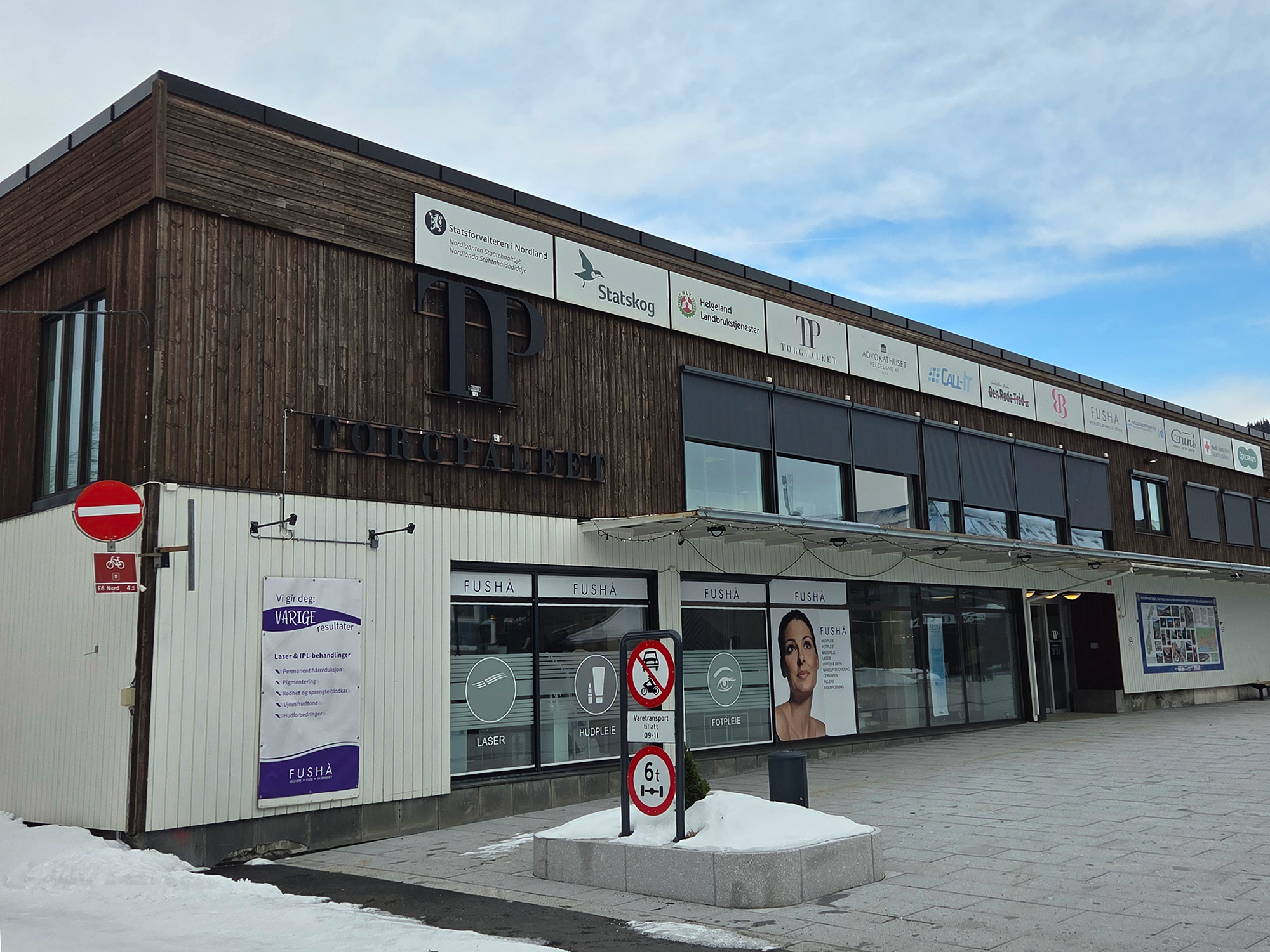 Bygning med to etasjer og flatt tak. Nedre del er hvit og høyre del er mørk brun.