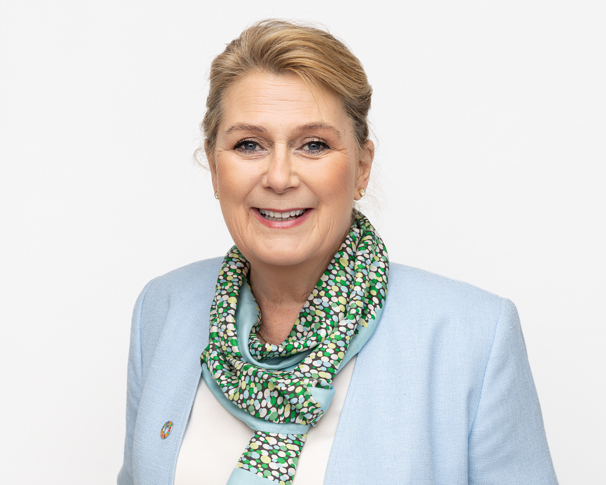 Portrettfoto av smilende dame i lyse klær. 