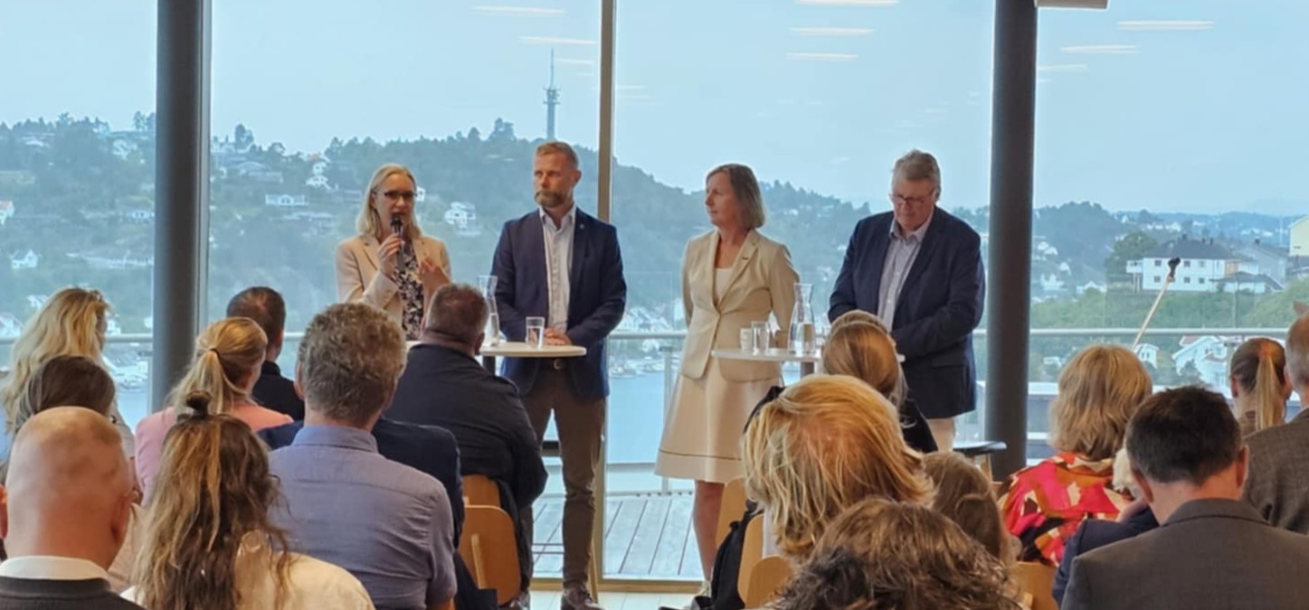 Paneldeltagere med salen i forgrunnen.