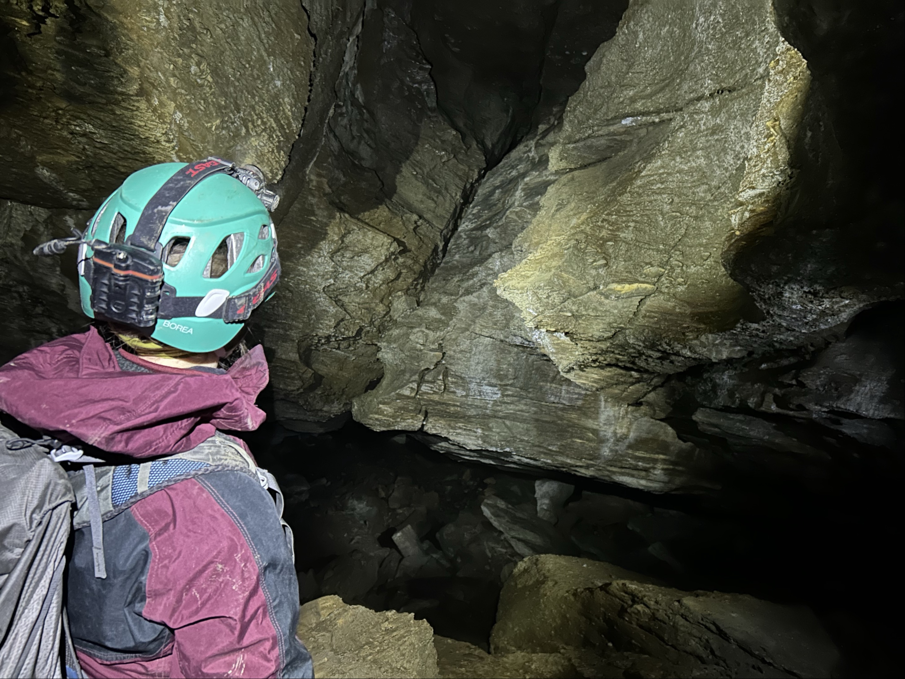 Eit bilete av ein person med hjelm som er inne i ei grotte.