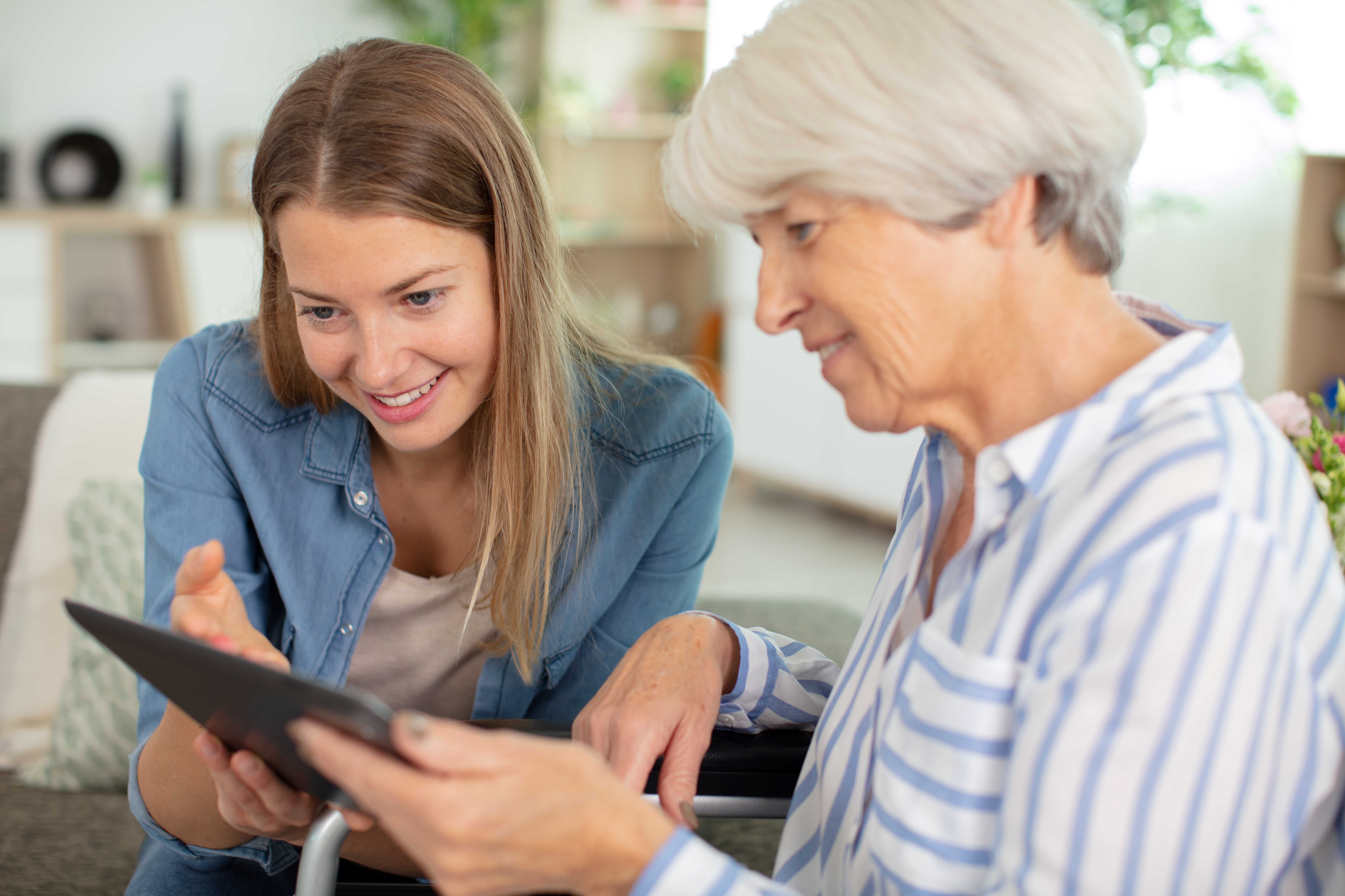 Ung kvinne og eldre kvinne ser på ein Ipad i lag