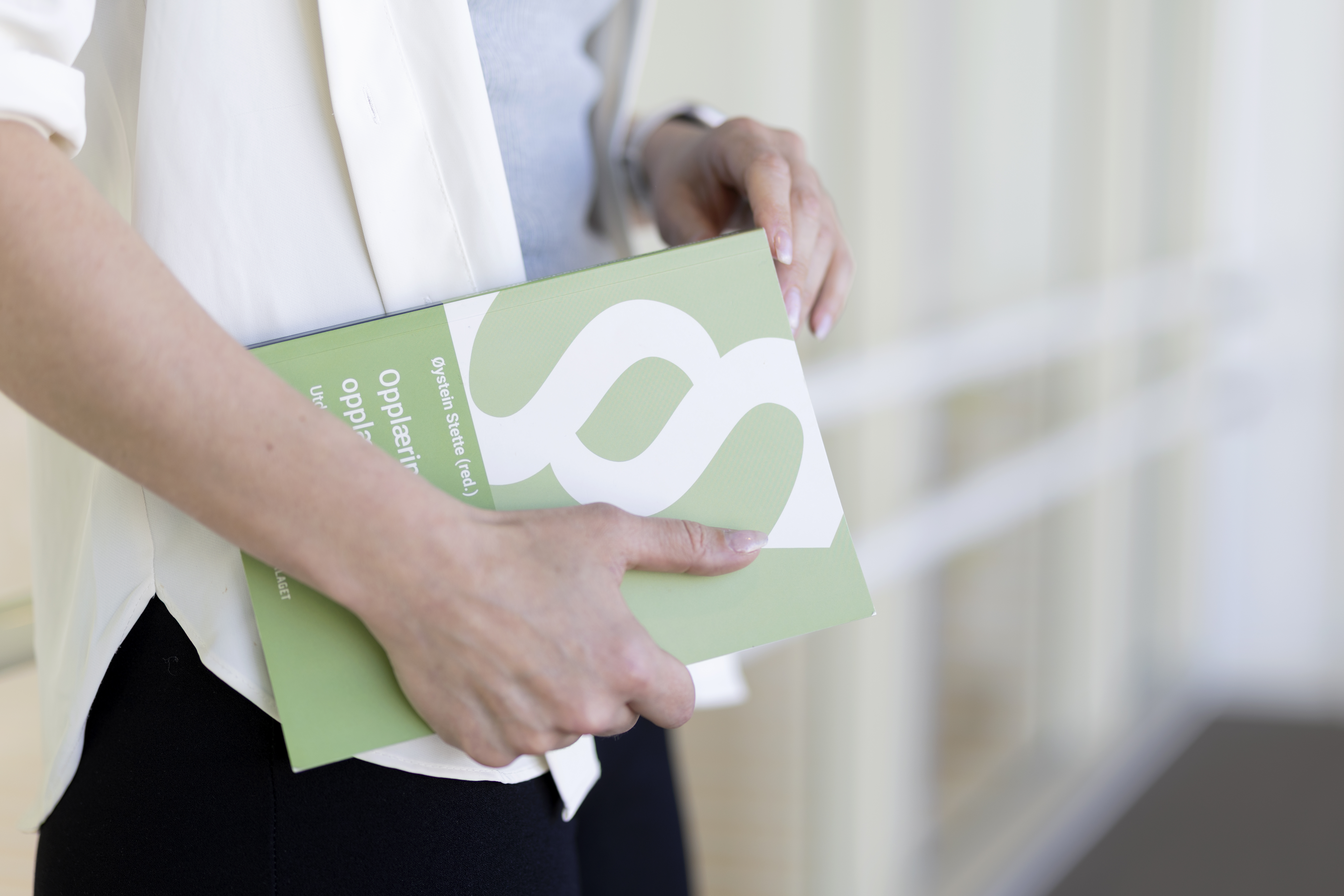 Bilde av person som holder opplæringsloven (bok) i hendene.