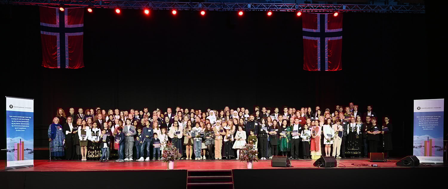 Stor gruppe mennesker som står oppstilt på en scene.