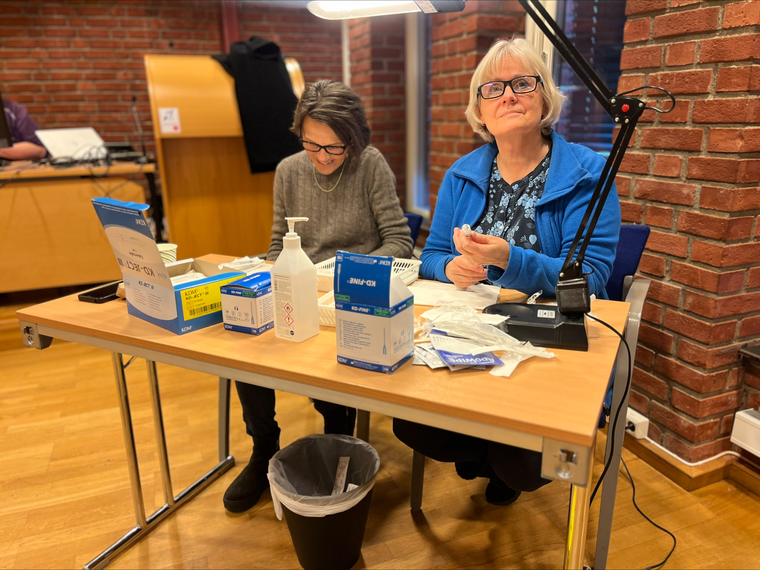 Frivillige pensjonerte sykepleiere Margret Bruvik og Gunn Haugstulen klargjør vaksiner. Foto: Ragne Stauri. To sykepleiere klargjør vaskine