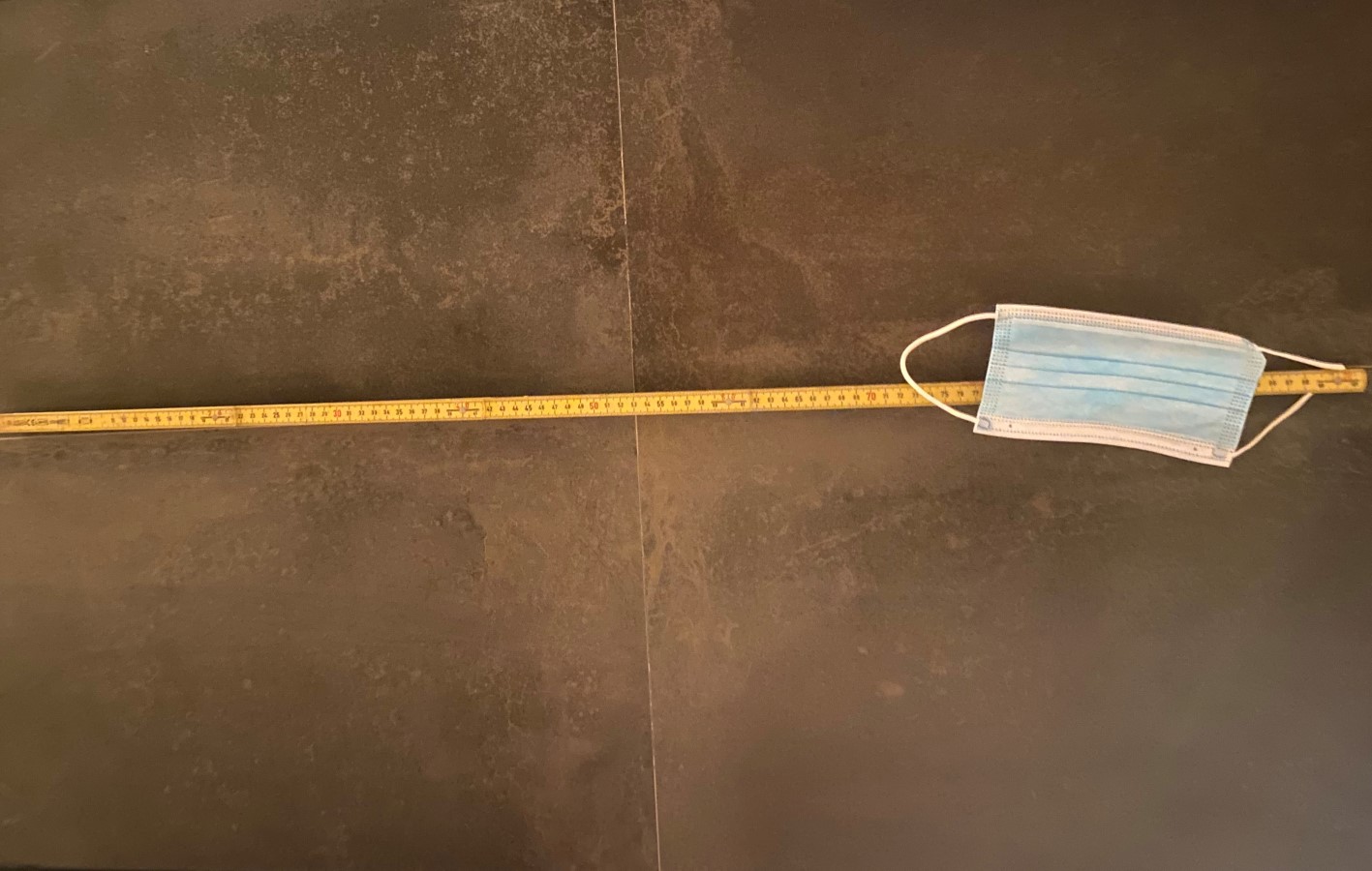 Illustrasjonsfoto av munnbind som ligger på bakken oppå en meterstokk