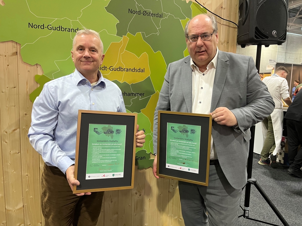 To karer som holder hvert sitt signerte matløfte i glass og ramma