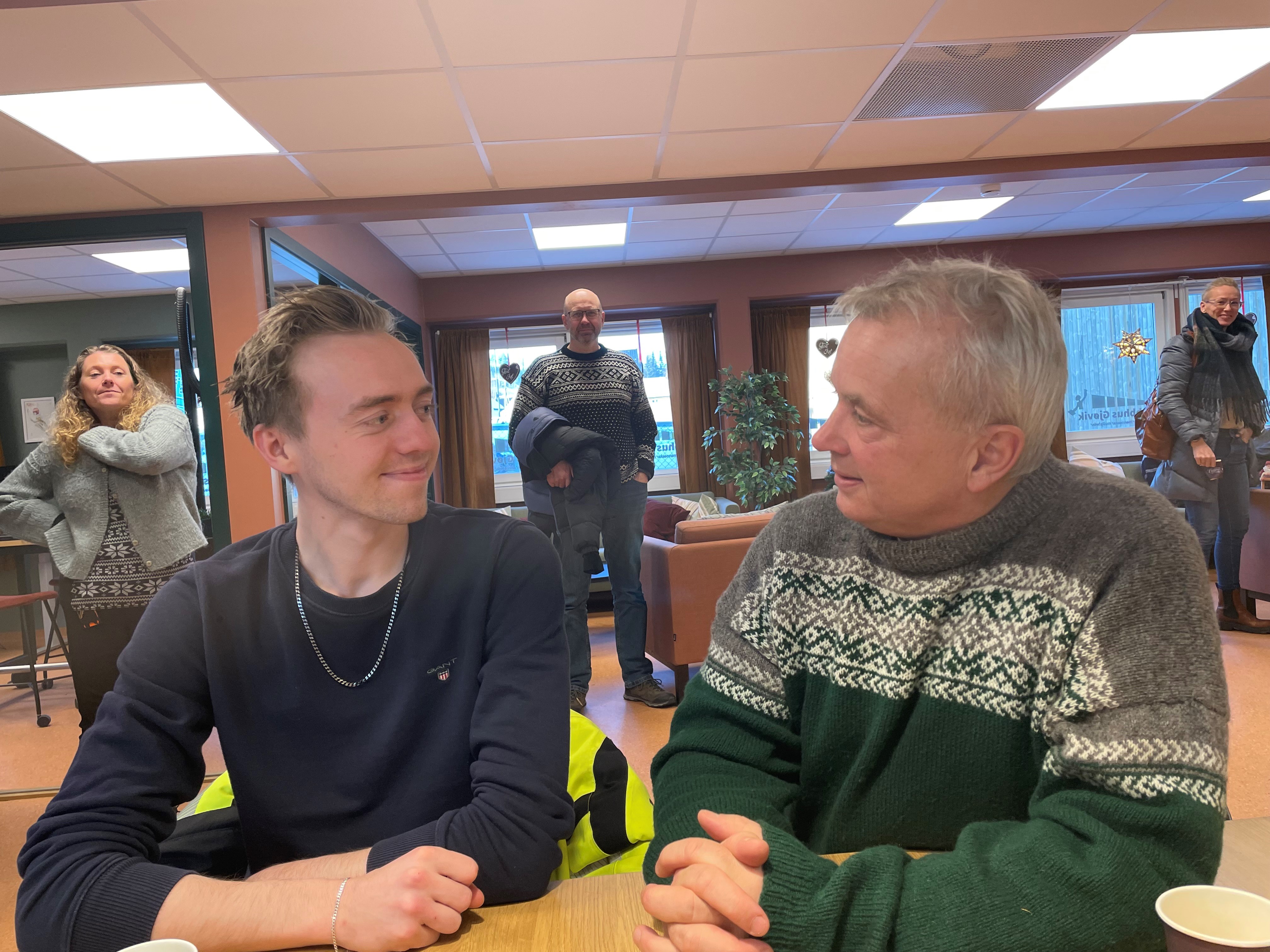 To menn som snakker sammen rundt et bord